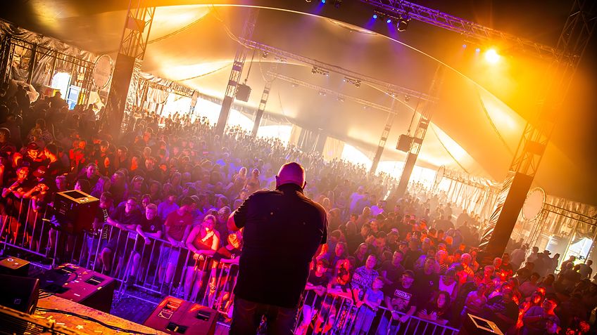Lichtshow in de festivaltent boven een vol publiek