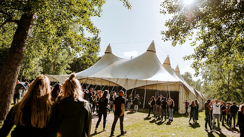 Kalahari festivaltent in woestijnzandkleur tussen de bomen